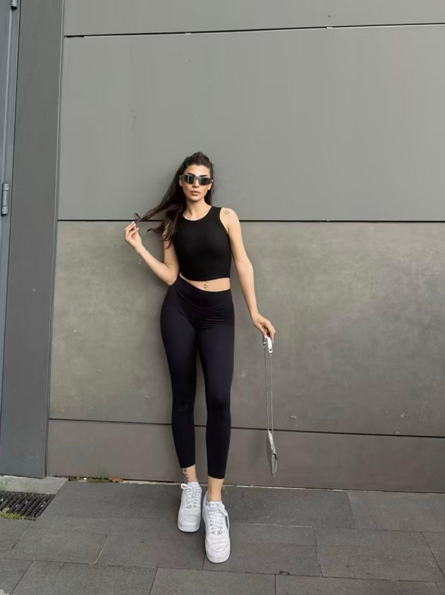 Top noir col halter en maille côtelée porté par une femme (modèle Haut Nilya)