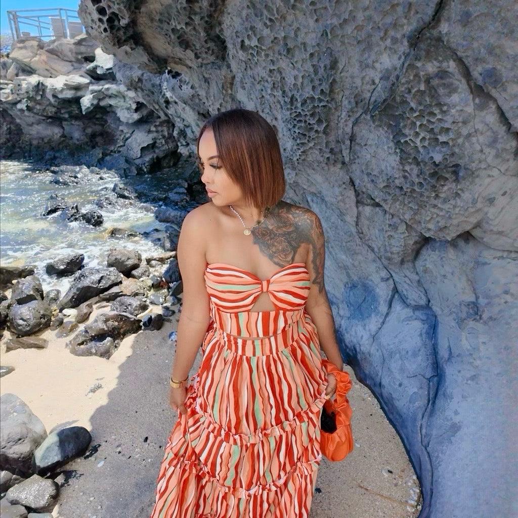 Femme portant un ensemble jupe longue orange à motifs multicolores avec haut assorti sans manches