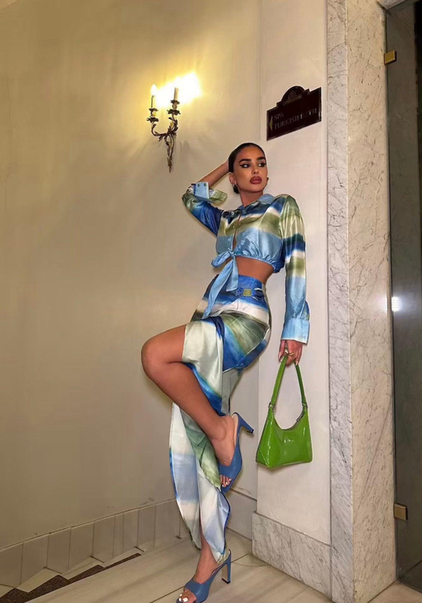Femme portant un ensemble veste nouée bleu-vert et jupe midi fendue assortie