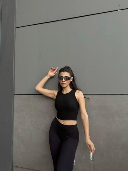 Top noir col halter en maille côtelée porté par une femme (modèle Haut Nilya)